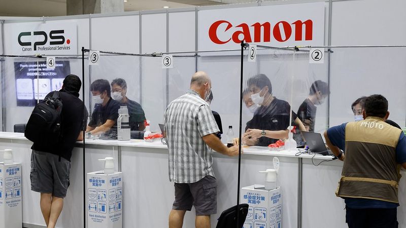 Klanten en servicetechnici bij de stands van Canon Professional Services op een evenementenlocatie.
