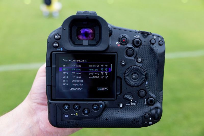 A user's hand holds an EOS R1 with the Connections settings screen displaying multiple sets of configurations.