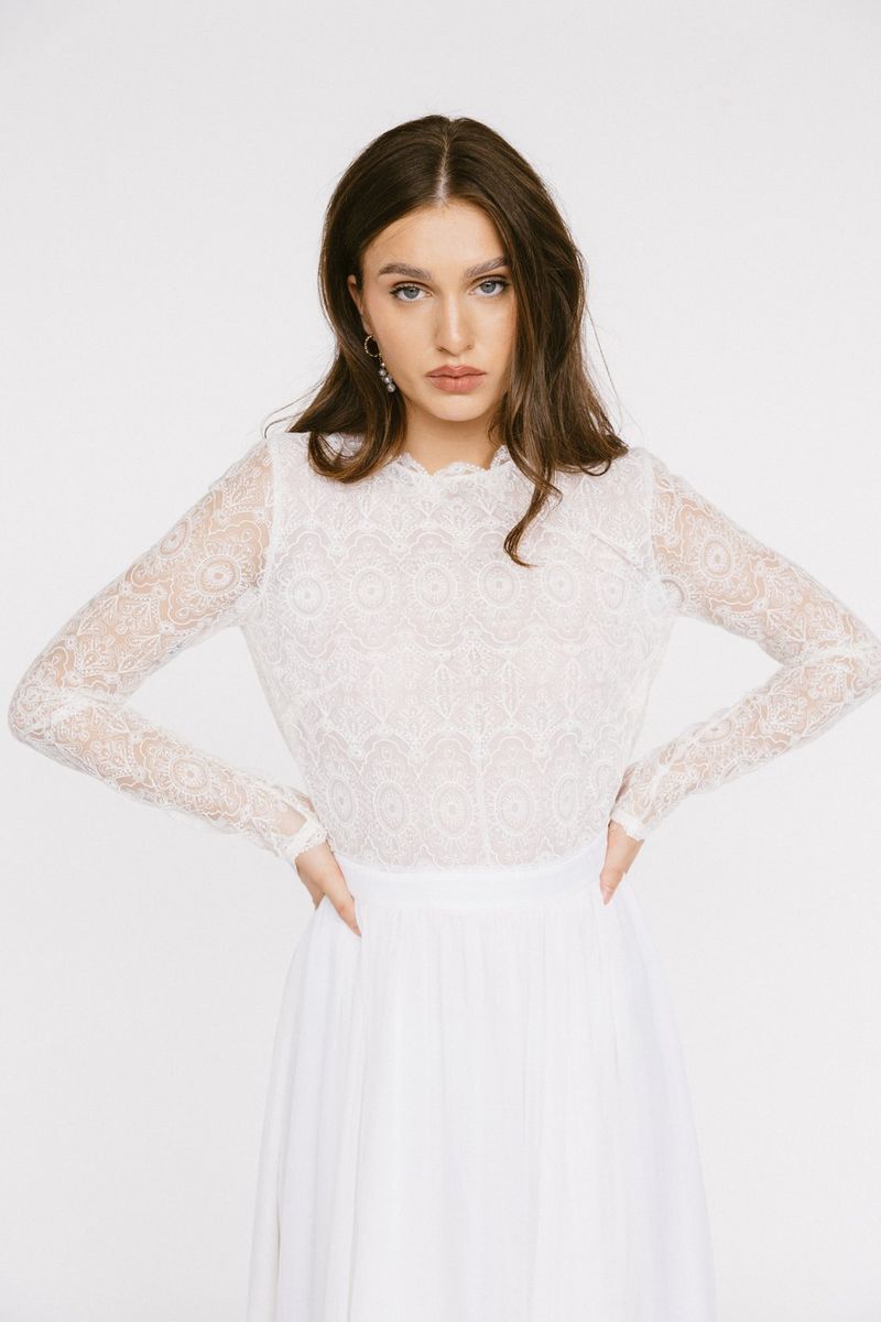 Een donkerharig model in een witte bruidsjurk kijkt naar de camera. Gefotografeerd door Julia Blumenthal en Gil Gropengießer met een Canon EOS R6 Mark II.