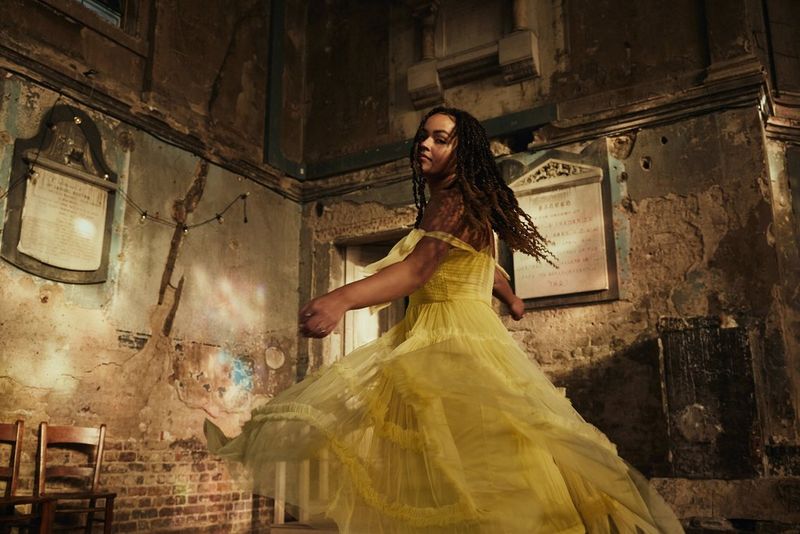 A figure is captured mid-movement, their hair and yellow dress fanning out around them in a photo taken by Ian Hippolyte on a Canon EOS R8.