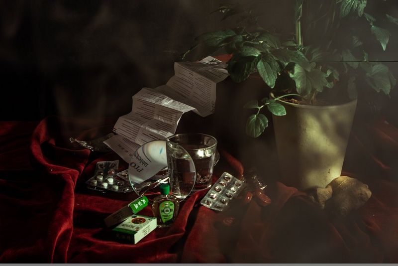 Pills and other medication arranged in a still life, spread across a red cloth.