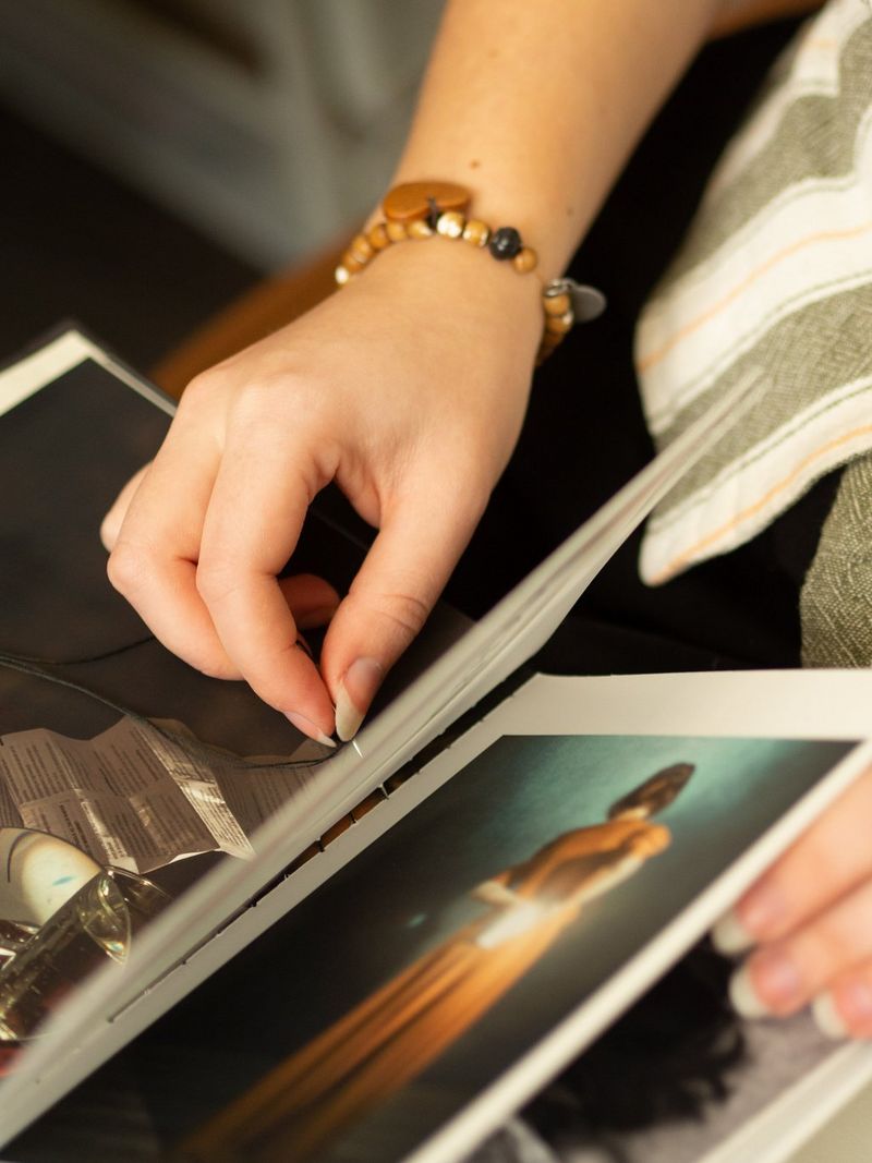 A woman carefully sewing pages of a handcrafted zine together.