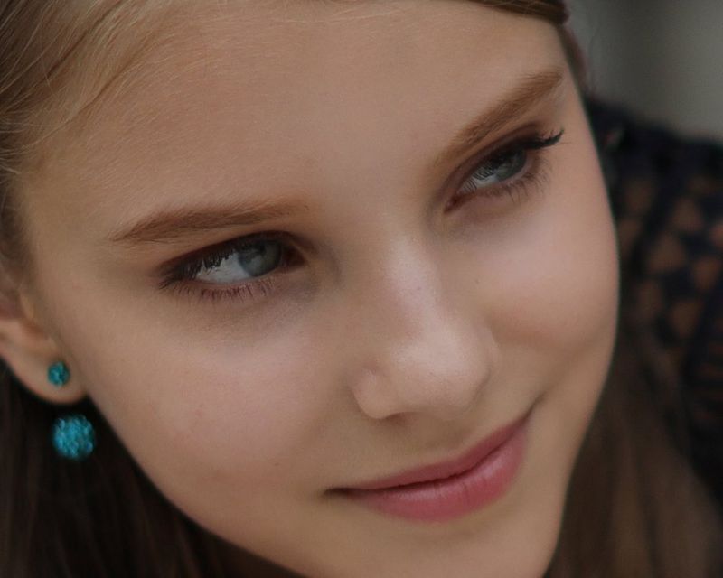 Een detail van een foto van een jonge vrouw die uit het raam leunt en opzij kijkt.