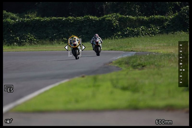 Due moto in corsa viste attraverso il mirino. Sulla moto in primo piano vi sono un cerchio arancione e un riquadro AF.