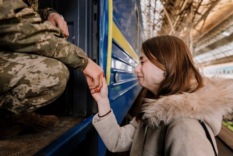 A woman cries as she holds the hand of a soldier who is sitting in a train, photographed by Ilvy Njiokiktjien.