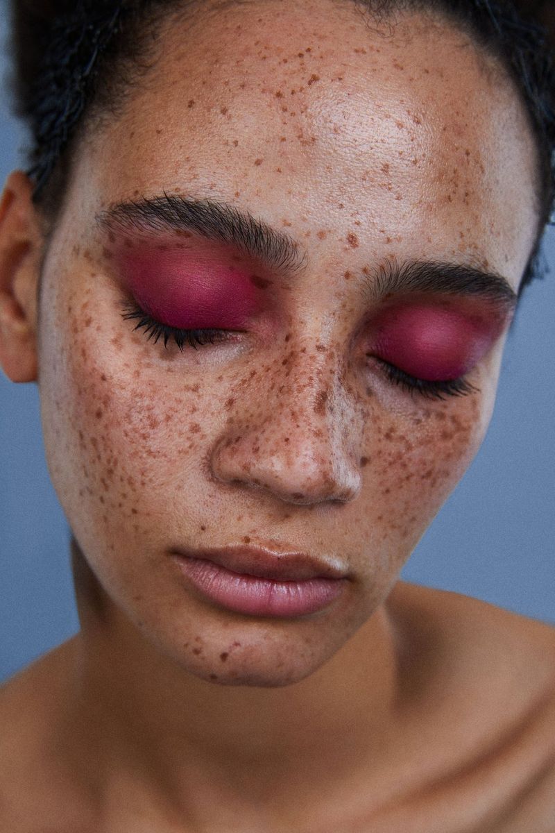 A close-up of a woman's face, her eyes closed showing pink eyeshadow, taken on a Canon EOS 5D Mark IV by Kid Circus.