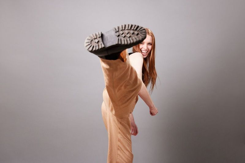 A woman smiles as she kicks her leg towards the camera, taken on a Canon EOS R5 by Kid Circus.