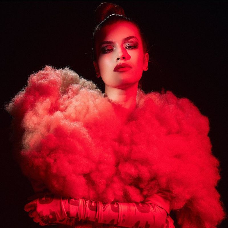 A model is bathed in red light against a black background