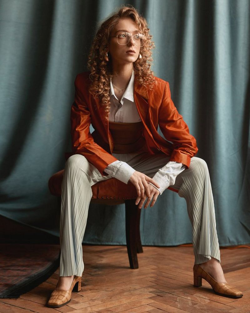 A woman sits on a stool leaning forward and resting her elbows on her knees, in a photo taken by Jaroslav Monchak on a Canon EOS R5.