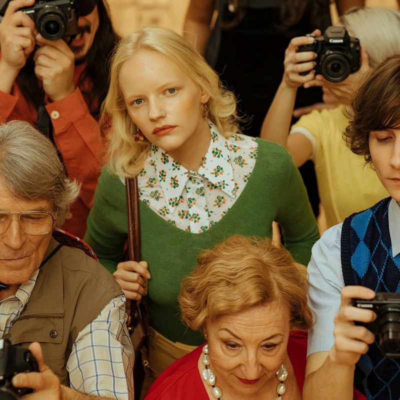 A woman in 1970's-style clothes looks up from a crowd in a shot from Javier Cortés's fashion film, Beauty is Subjective.