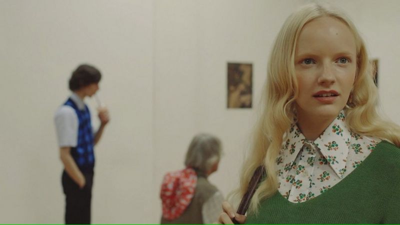 In a still from Javier Cortés' fashion film, Beauty is Subjective, a young model stands in an art gallery, among people dressed in vintage clothes.