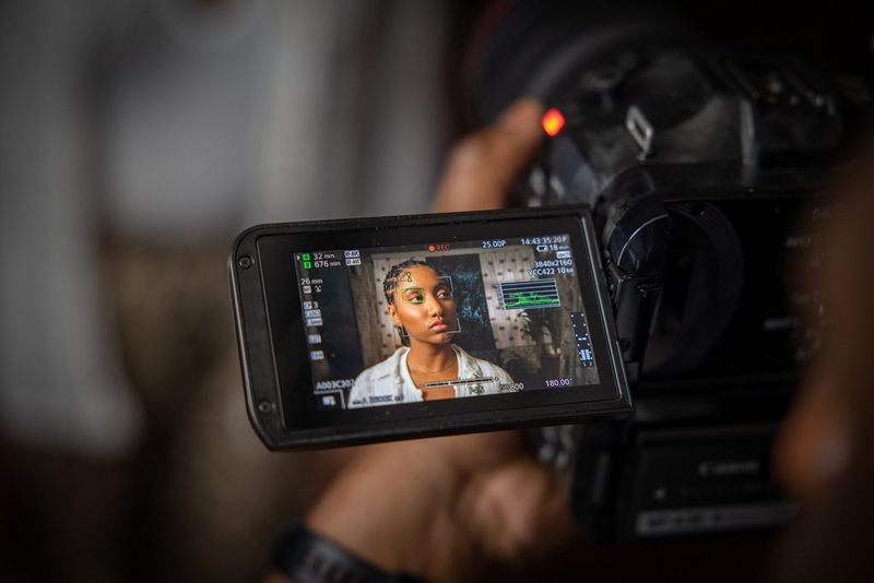 Сенсорный экран камеры Canon EOS C70, на котором отображается лицо женщины с графическими индикаторами функции помощи при фокусировке.