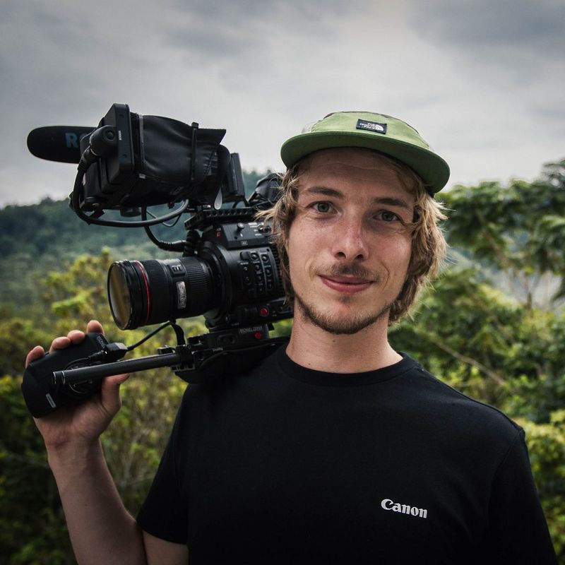 Filmmaker Michael Zomer in a forest setting with a Canon camera balanced on his shoulder.