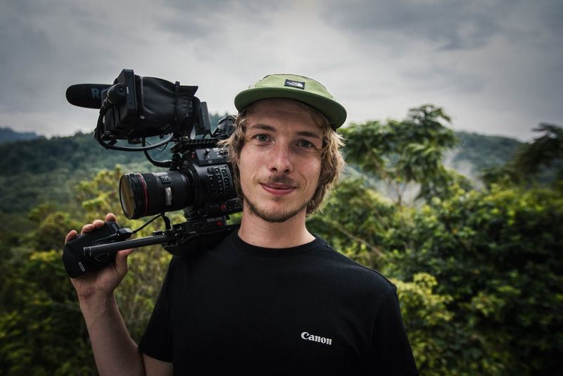 Filmmaker Michael Zomer in a forest setting with a Canon camera balanced on his shoulder.