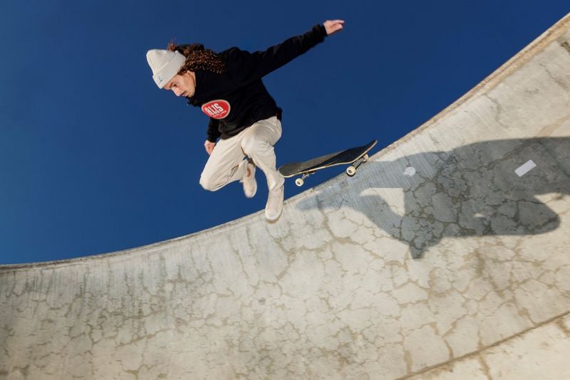 Een skateboarder die boven aan een helling van zijn board valt, op een zonnige herfstdag.