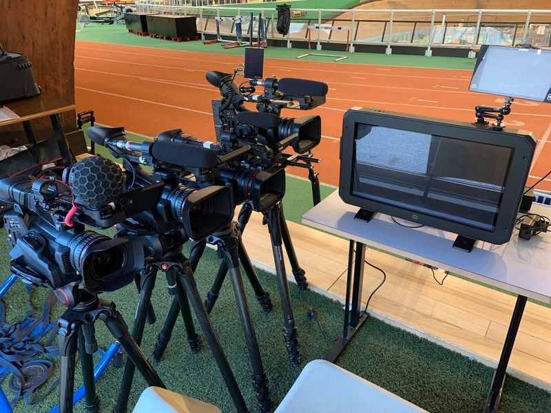 Ряд видеокамер Canon XF705 для многокамерной съемки рядом с крытой беговой дорожкой.