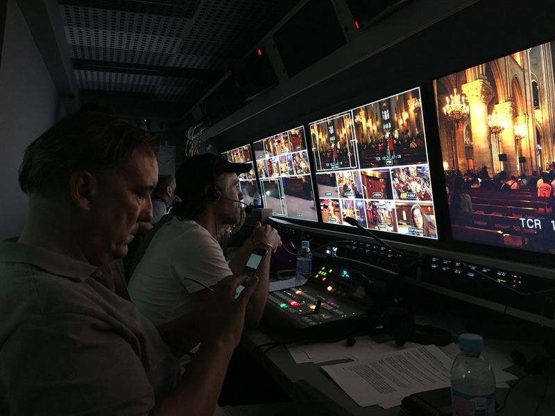 Члены съемочной группы смотрят на ряд экранов, демонстрирующих изображения с нескольких камер, которые снимают церковную службу.