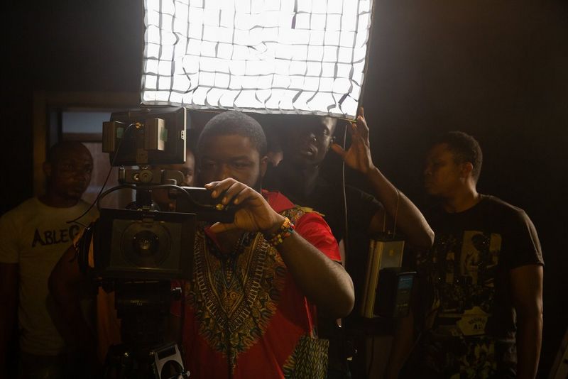 Режиссер Даниэль Эхимен в оранжевой рубашке с узором работает с камерой, а за спиной у него световой экран.