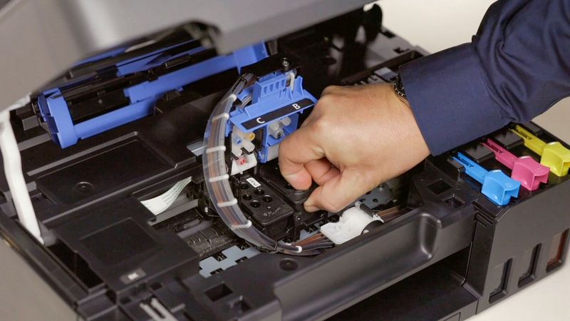 A hand changing the print head in a Canon printer. 