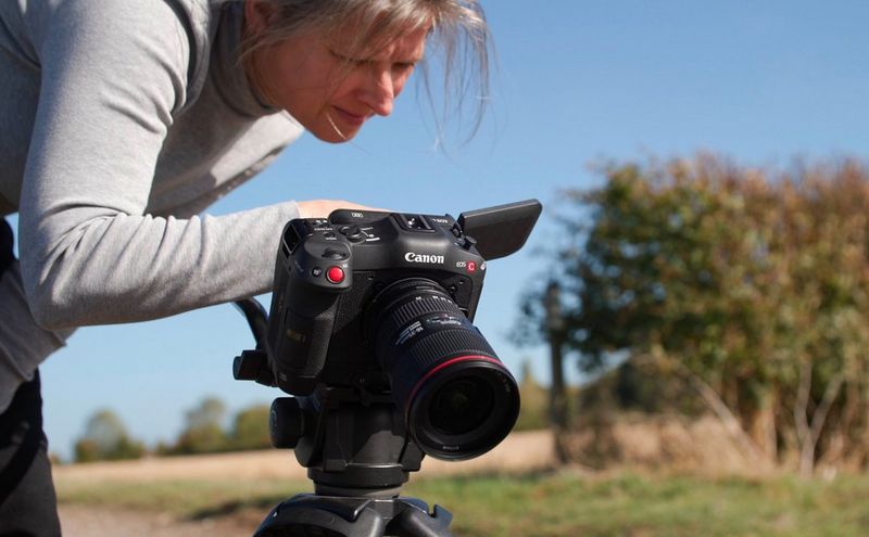 La regista Tania Freimuth si sporge su una videocamera Canon EOS C70, installata su un treppiede.