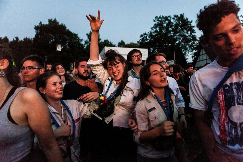 Een groep tieners lachen en dansen buiten rond, in een groep dicht op elkaar.
