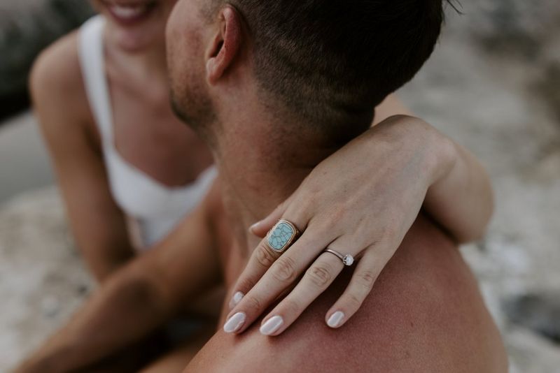 A woman’s left hand resting on a man’s shoulder, with her rings in sharp focus and the rest of the image falling out of focus. Taken on a Canon EOS R5 by wedding photographer and videographer Jo Greenfield.