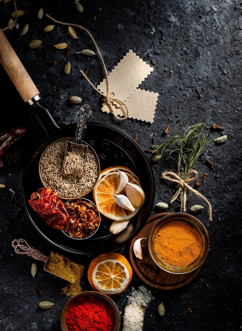 A top-down shot of herbs, dried fruit and spices laid out on a rough black surface.