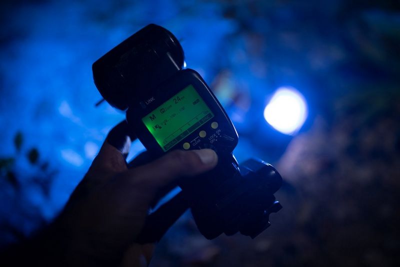 Вспышка Canon Speedlite 600EX II-RT в руке. Темный задний план залит синим светом.