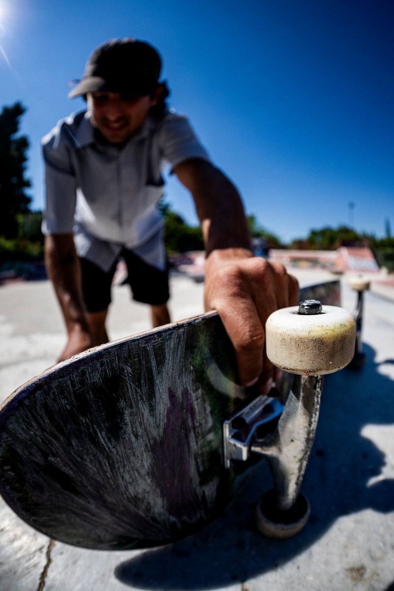 A frame-filling fisheye photo of a skateboarder reaching for his skateboard, taken using a Canon RF 7-14mm F2.8-3.5L FISHEYE STM lens.