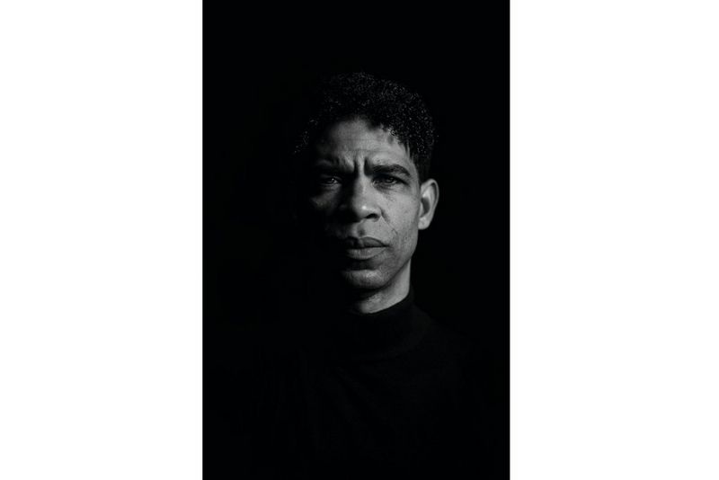 Een zwart-witportret van een man die recht in de camera staart.