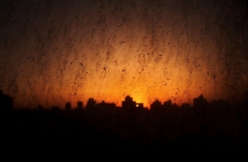 The Cairo skyline silhouetted against the setting sun, which has turned the sky bright orange.
