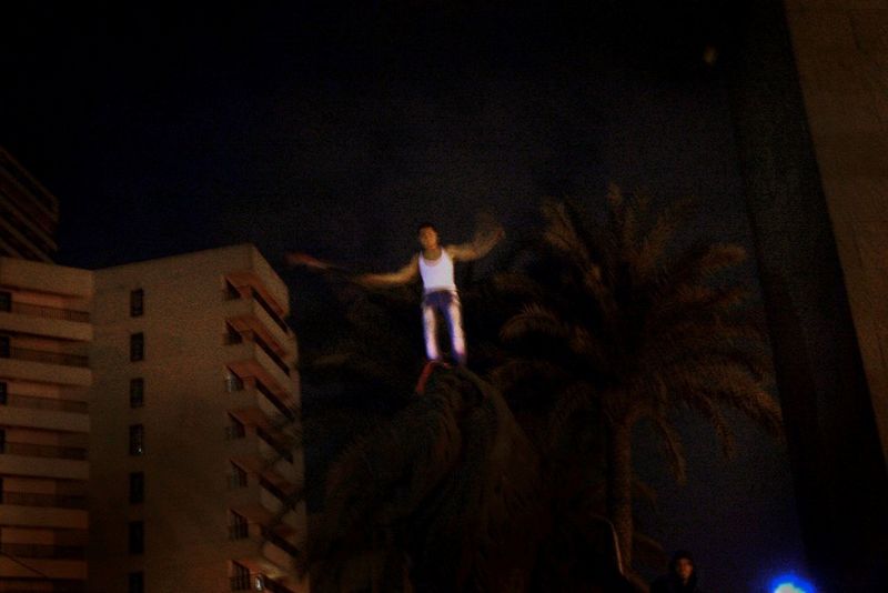 A man standing on a statue waving the Egyptian flag during a night-time protest in Cairo. 