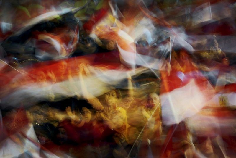 A blurred shot of female protestors waving flags in Tahrir Square, Cairo.