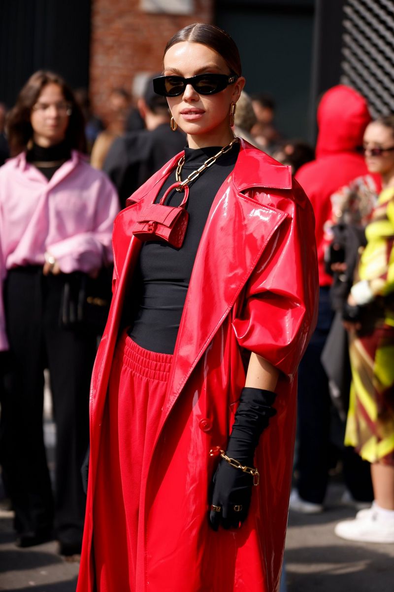 A woman wearing a black top, red bottoms, red jacket, black gloves and sunglasses looks at the camera. Taken by fashion photographer Leo Faria using the Canon EOS R5. 