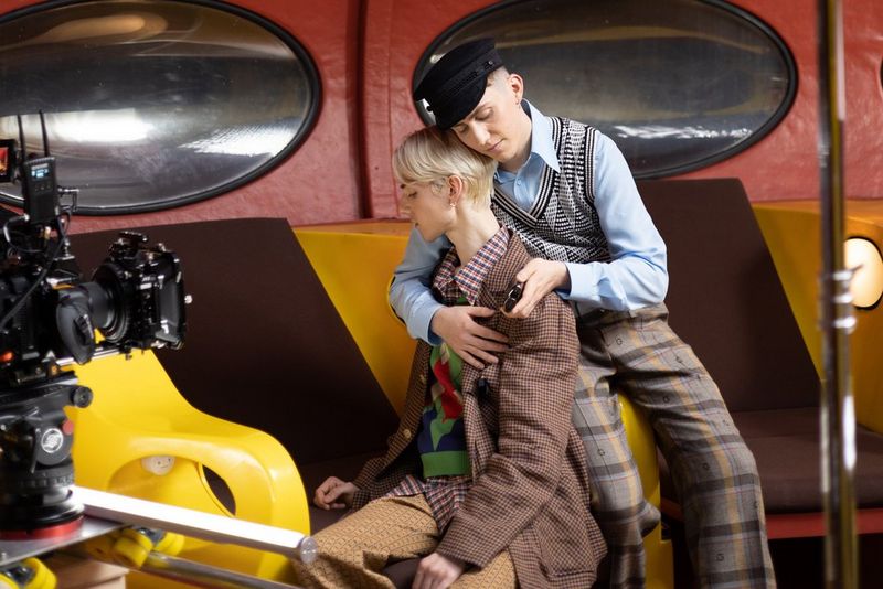 Два человека сидят вместе перед кинокамерой Canon на съемочной площадке — один из них обнимает второго за спину.