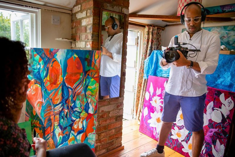 Filmmaker Simeon Quarrie filming in an art studio with the Canon EOS C70 camera. The studio is filled with large, colourful canvases.