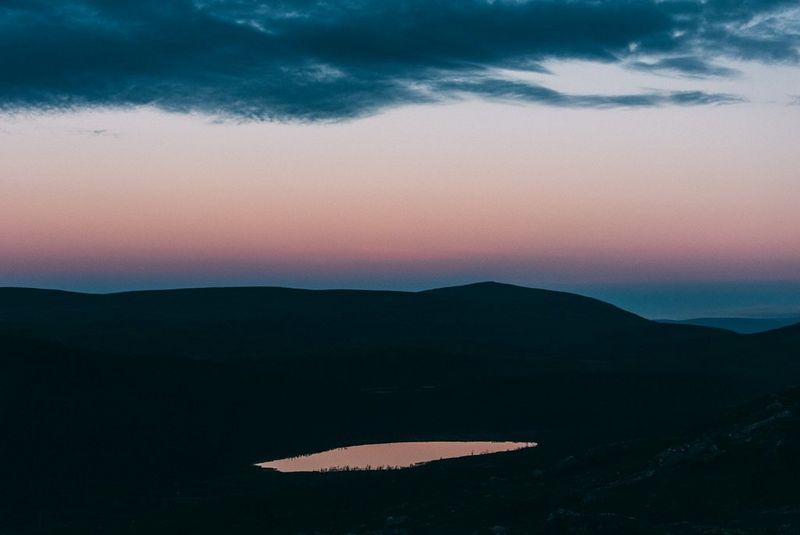 Een roze zonsondergang boven een roerloos meer.