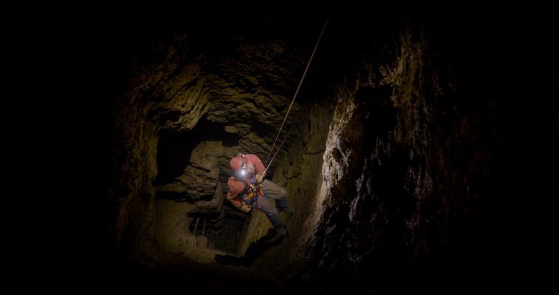 A film still of a man abseiling down an old mineshaft, looking up at his ropes, in a still from Daniel Simpkins' current documentary project set in abandoned Cornish mines, captured on the Canon EOS C70 cinema camera. 