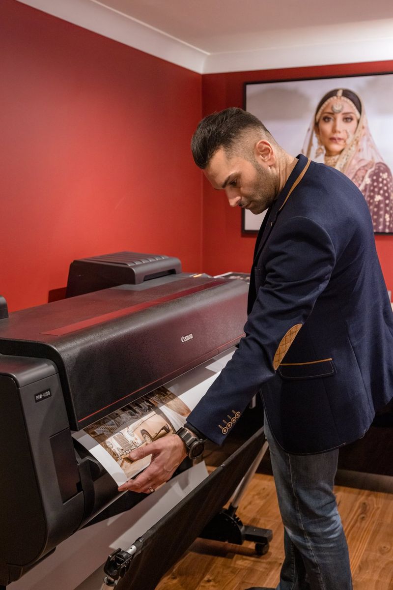 Photographer Sanjay Jogia stands over a Canon imagePROGRAF PRO-4100 printer, as a large print of a wedding photo emerges.