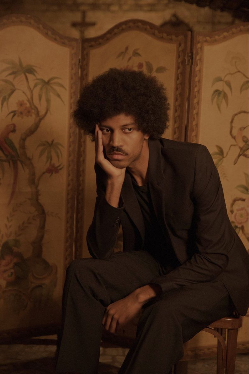 Een figuur zit op een stoel en leunt voorover met de elleboog op de knie en kin in de hand in een portret gemaakt met een Canon EOS-1D X Mark II door Wanda Martin.