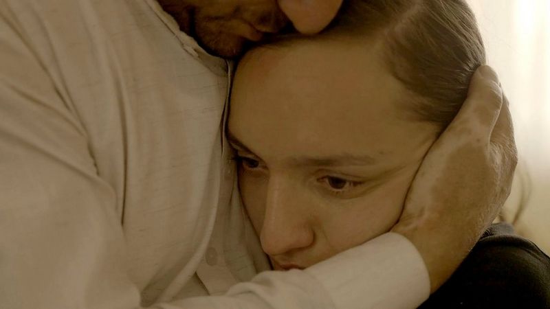 A still from In Her Hands showing a close-up of Zarifa Ghafari's face as she is embraced by a man, filmed by Marcel Mettelsiefen. 