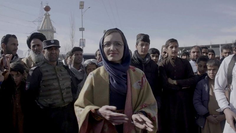 A still from In Her Hands showing Zarifa Ghafari with a large group of people, filmed by Marcel Mettelsiefen.