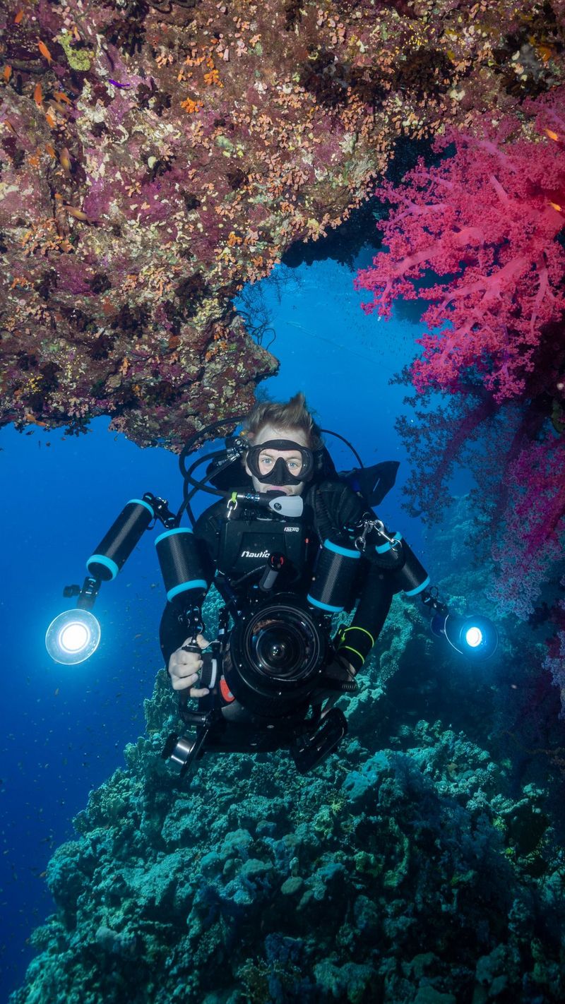 Il videomaker subacqueo Nicolai Deutsch manovra il suo rig subacqueo tra colorate formazioni coralline.