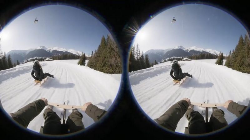 Due immagini fisheye affiancate di una persona in slittino, con delle montagne innevate in lontananza. Il manubrio e i piedi del regista sono visibili in primo piano.