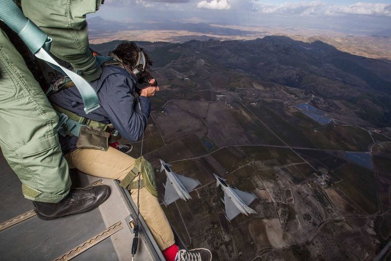 Aerial photographer Massimo Sestini photographs two jets flying below him from the open cargo door of an aircraft hundreds of metres in the air. 