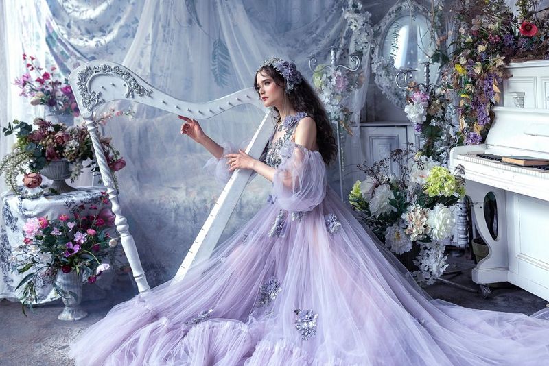 Une femme vêtue d'une robe mauve joue avec une harpe blanche. Photo prise par Menna Hossam avec un appareil photo Canon EOS R5.