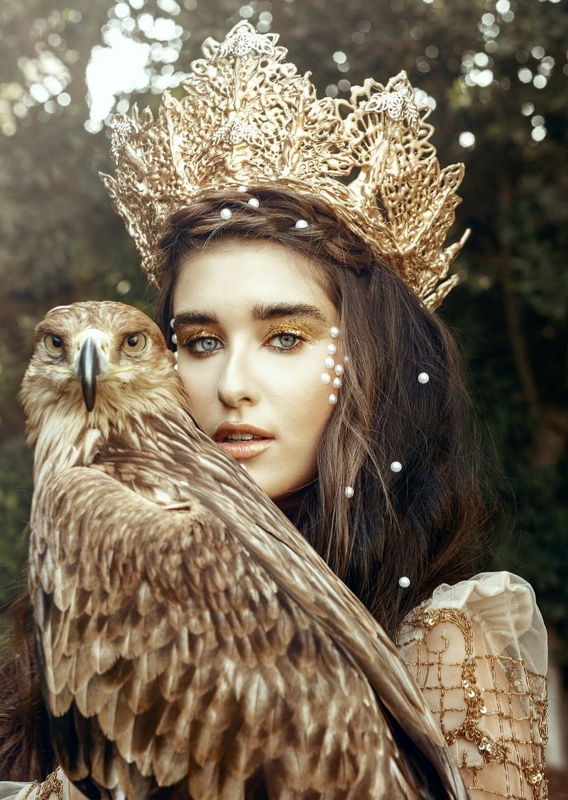 Une femme portant une couronne regarde droit dans l'objectif de l'appareil photo tandis qu'un faucon est posé sur son bras gauche. Photo prise par Menna Hossam avec un Canon EOS R.