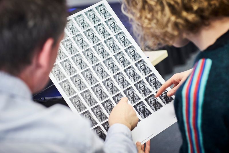 Two people examine a sheet of variations of a portrait photo produced using the Pattern Print feature in Canon's PPL software.