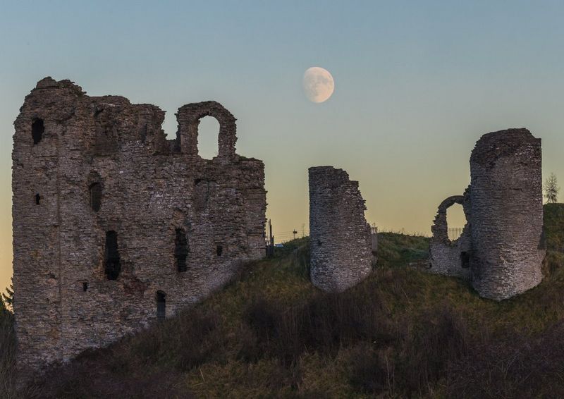 Растущая Луна высоко в небе за руинами замка Клан в графстве Шропшир, Великобритания; снято Эндрю Фьюзеком Питерсом.