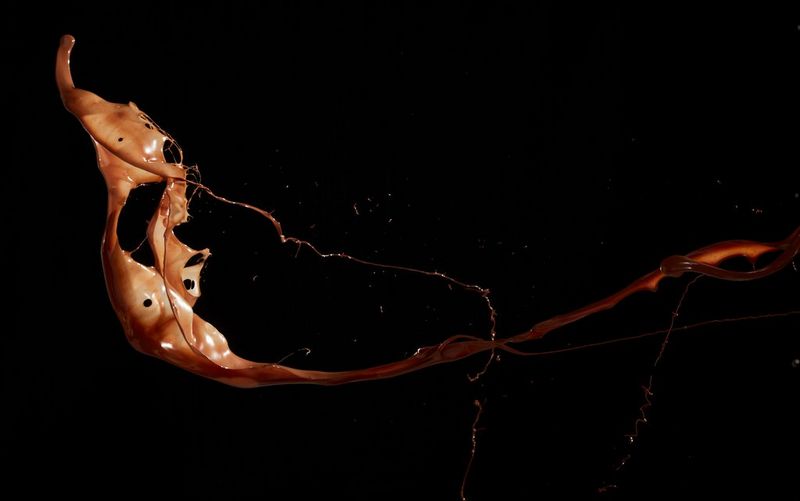 Melted chocolate captured mid-splatter against a black background.